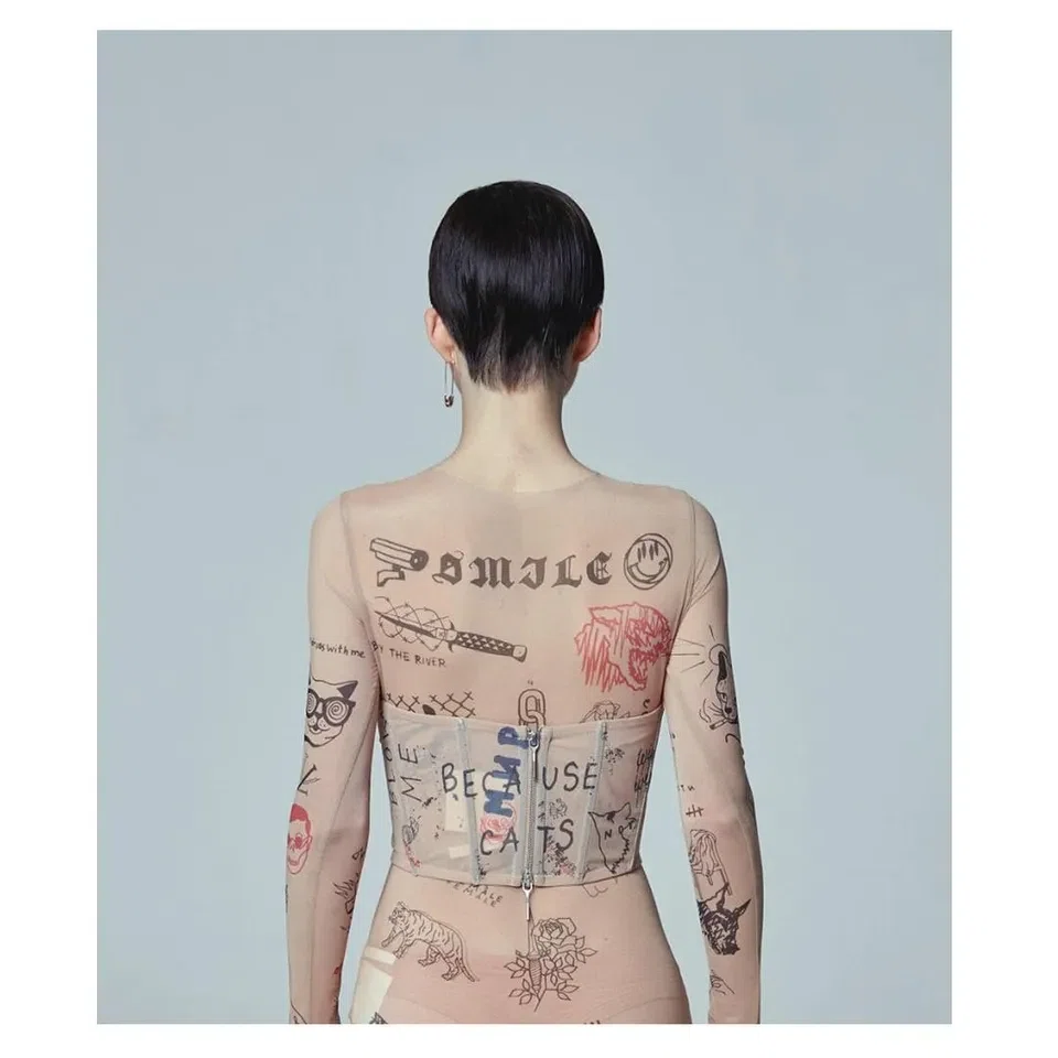 modelo de espaldas con una licra que simula tatuajes grabados en la piel. La moda y el tatuaje.