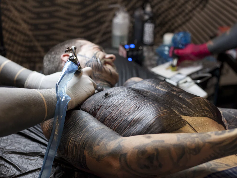 Brutal Black Project. Tatuando sin piedad el torso de un cliente en un estudio de tatuaje mientras aguanta el dolor del proceso
