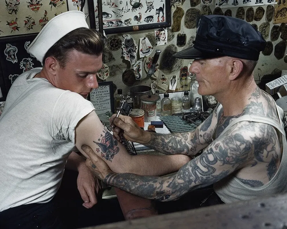 Artista tatuando a un marinero en el brazo. Cap Coleman flash tattoo