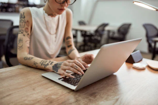 persona con tatuajes usando laptop