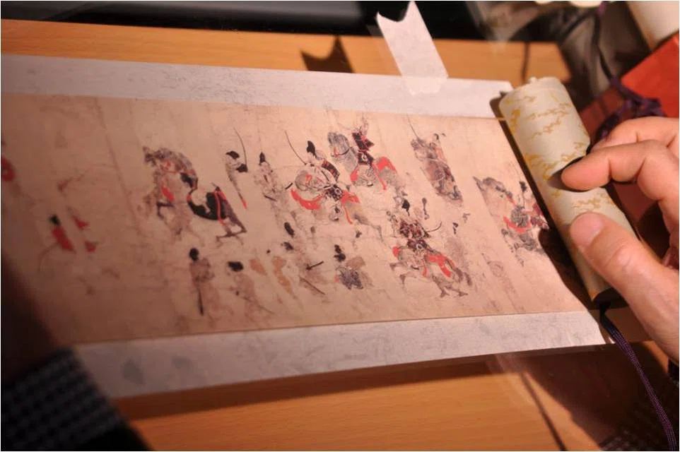 emakimono manga en un rollo de papel dibujdado con tinta negra y roja que representan batallas