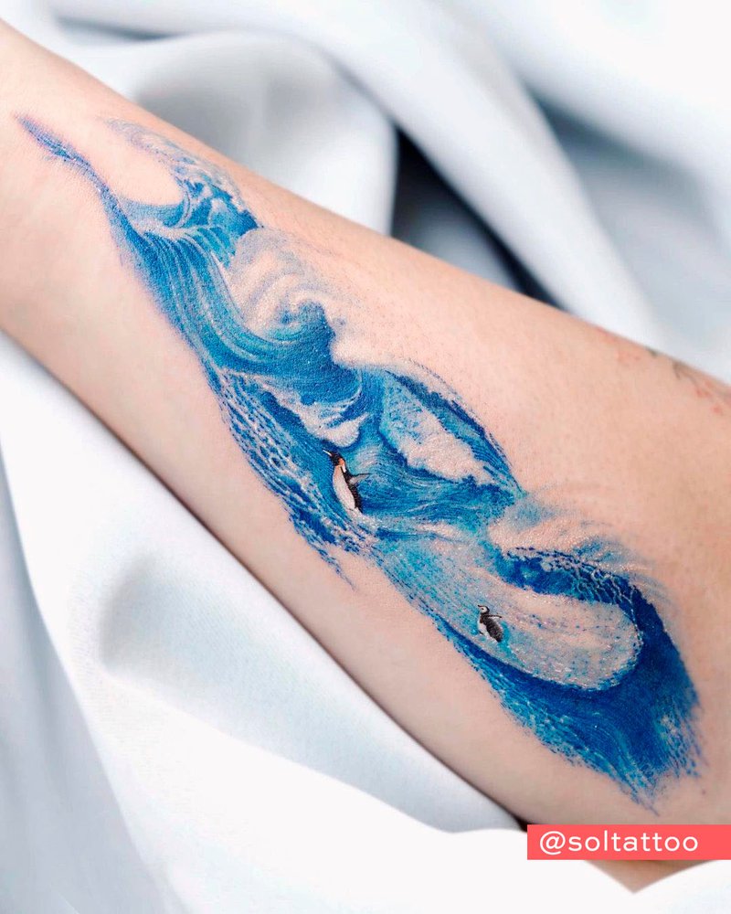 Tatuaje de una ola en tinta azul. Tatuaje en el antebrazo