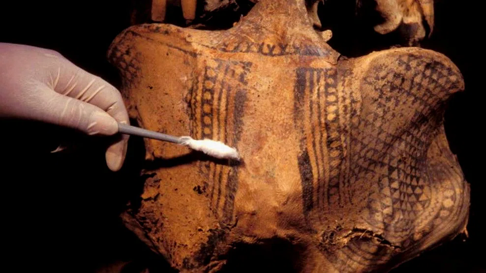 Arqueólogo analizando un cuerpo momificado con tatuajes grabados en la piel.