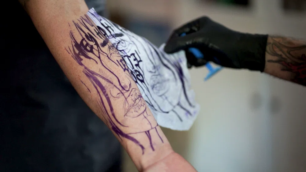 aplicando plantilla esténcil en la piel para transferir el diseño a tatuar